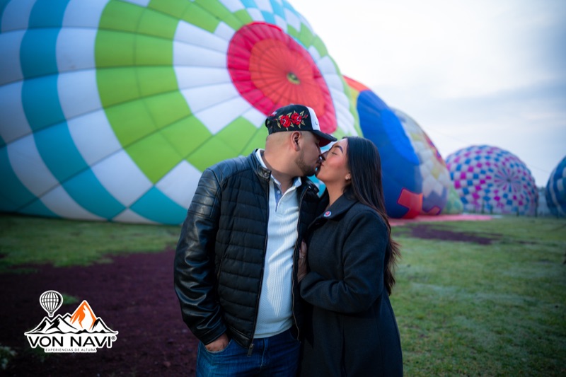 Pareja besándose entre globos aerostáticos coloridos en el amanecer de Teotihuacán